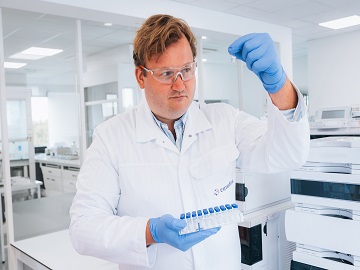 Eurofins employee examining vial as part of quality control testing for batch release 