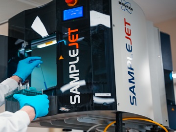 Laboratory worker inserting samples in NMR machine for spent media analysis