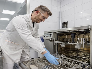 Employee performing reprocessing cleaning validation of medical devices Eurofins employee storing medical device in the stability storage room for stability testing
